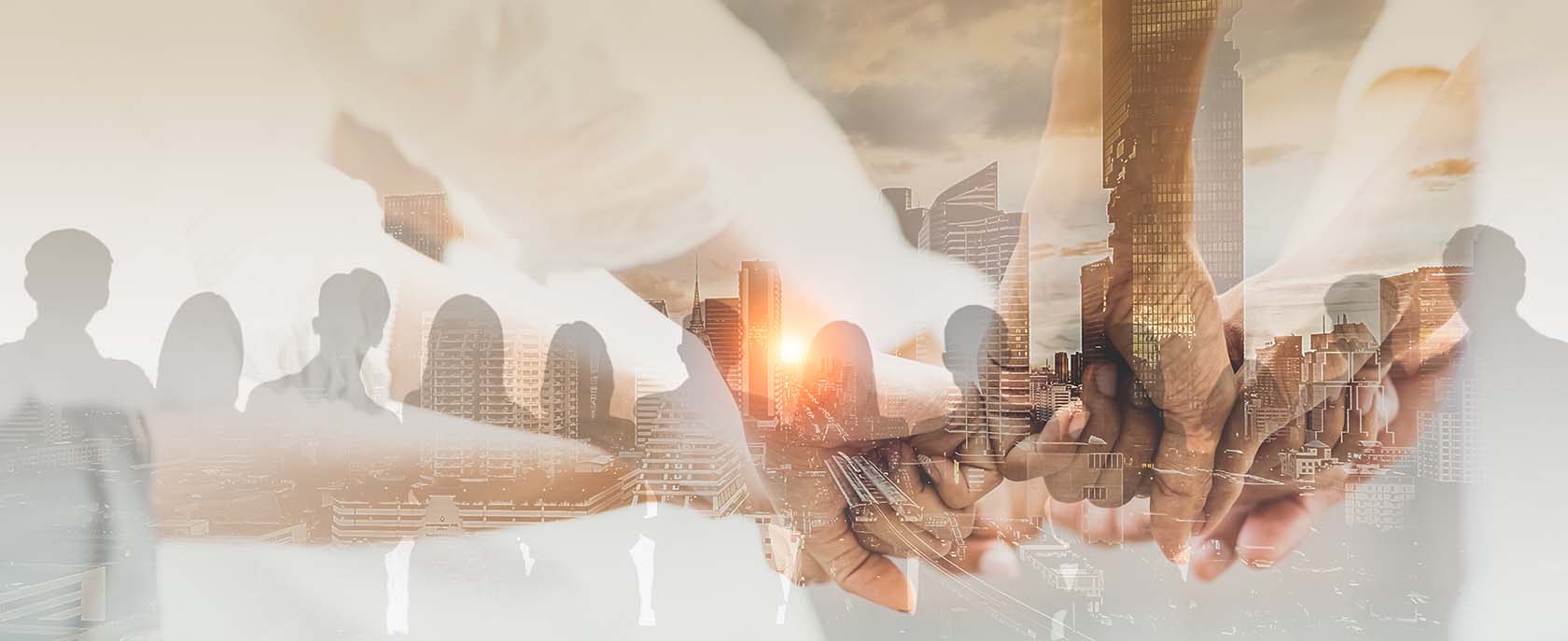 Double exposure of silhouettes of people looking at a skyline at sunset and a group of people holding hands